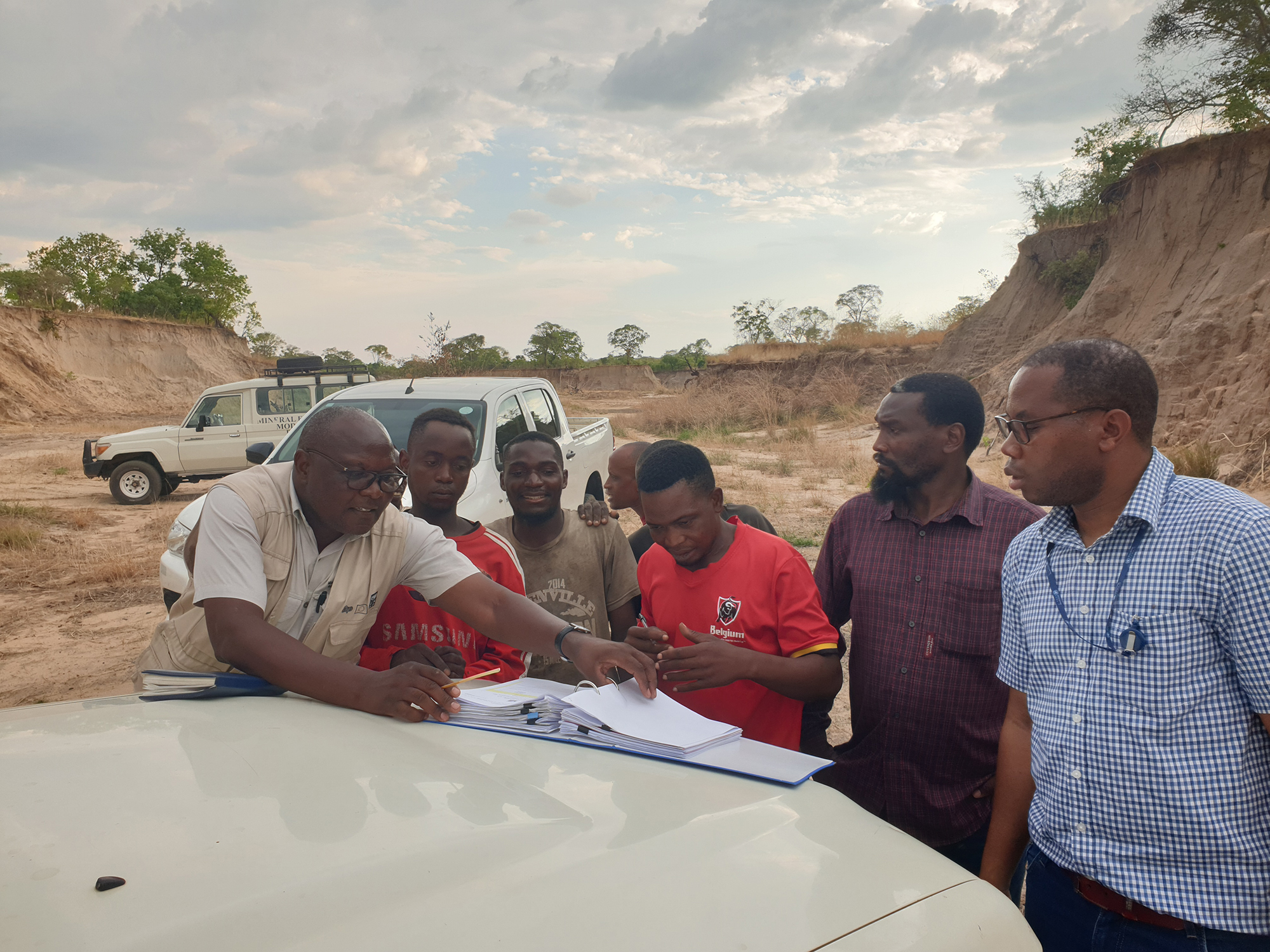 Government officials and Programme staff guiding artisanal and small-scale miner in filling an application form for a mining licence during a formalization mission in Livingstone, Zambia