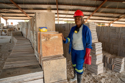 Artisanal and small-scale miner with cut flat dimension stones for construction at a stone processing facility in Lusaka, Zambia