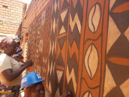 Tiébélé women applying the traditional mural painting on the LCM demonstration building in Ouagadougou