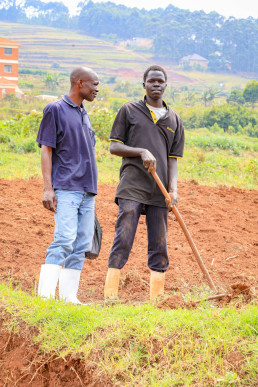 Two participants observing ongoing outdoor sessions at Kabale University, engaging with activities and demonstrations taking place on-site.