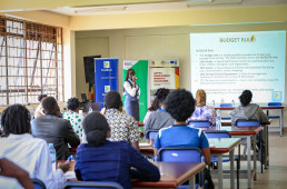 Indoor training session led by Ms. Kermudu Peace, Branch Manager at Gulu University, focusing on financial literacy and money management skills for youth participants.