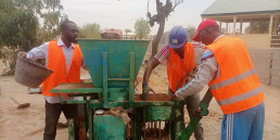 Trainees use a brick press to make stabilized earth bricks.