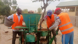Trainees use a brick press to make stabilized earth bricks.