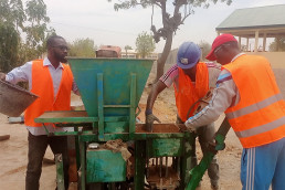 Trainees use a brick press to make stabilized earth bricks.