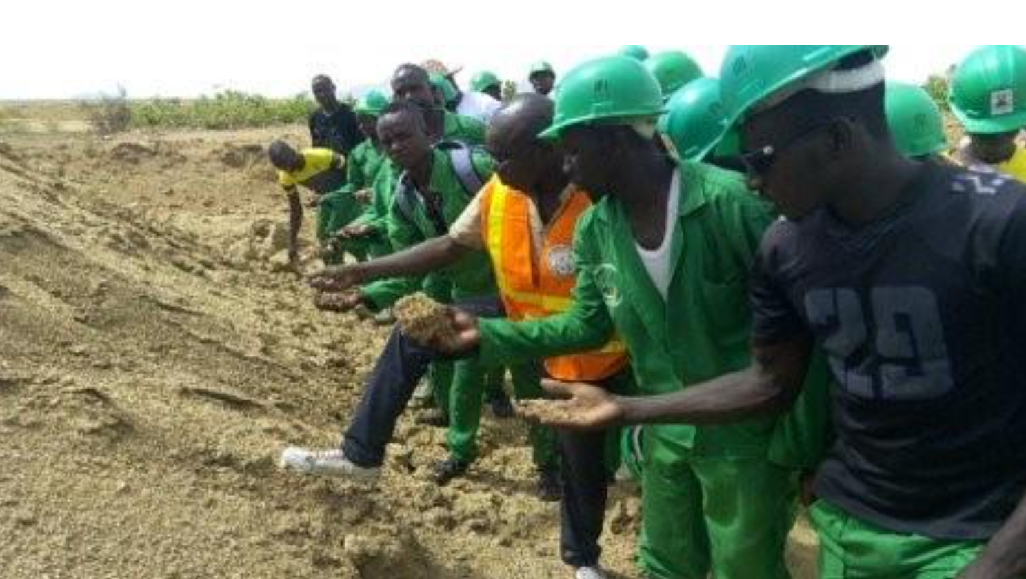 Wearing an orange safety vest, Ibrahim Djagra demonstrates to trainees how to identify and select the best local materials for producing stabilized earth bricks.